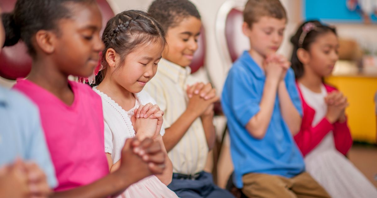 The above stock image shows children praying.
