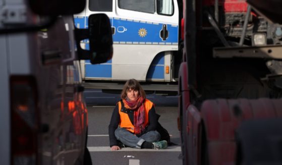 A climate activist sits with one hand super-glued to the asphalt as she and others block traffic at an intersection on Thursday in Berlin.