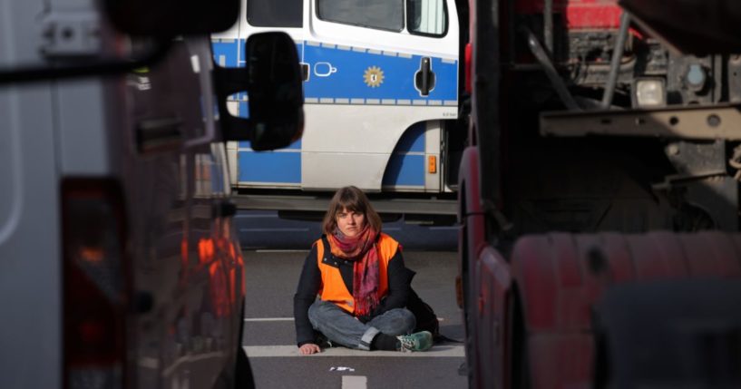 A climate activist sits with one hand super-glued to the asphalt as she and others block traffic at an intersection on Thursday in Berlin.