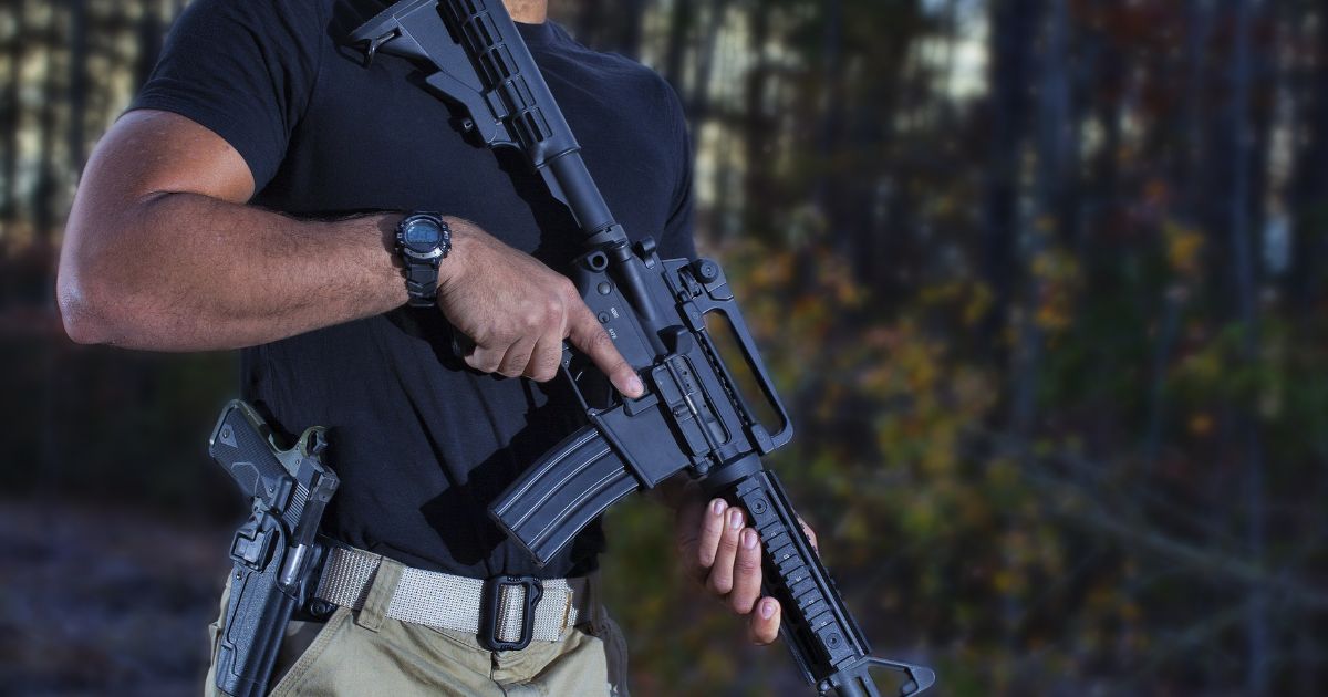 A man holds a rifle in the above stock image.