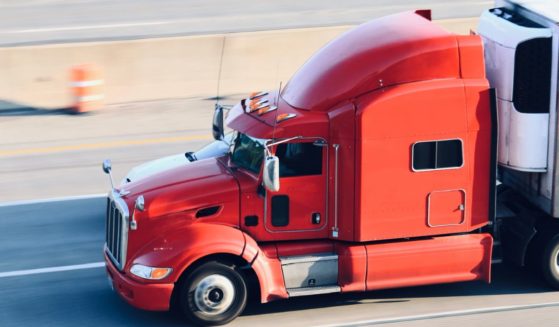 A semi truck drives on the highway in this stock image.