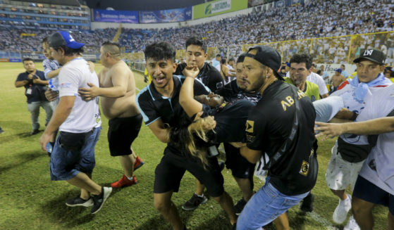 An injured fan, center, is carried on the field at the soccer stadium in San Salvador, El Salvador, after a stampede broke out during a soccer game on Saturday.