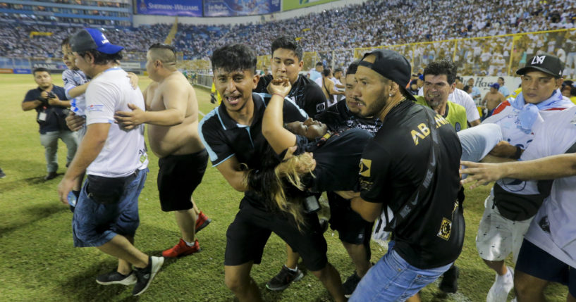 An injured fan, center, is carried on the field at the soccer stadium in San Salvador, El Salvador, after a stampede broke out during a soccer game on Saturday.