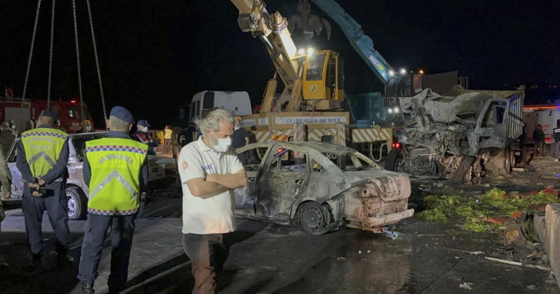 Turkish police officers and emergency personnel work next to burned vehicles after a crash late Saturday on the Iskenderun-Antakya highway in south Turkey.