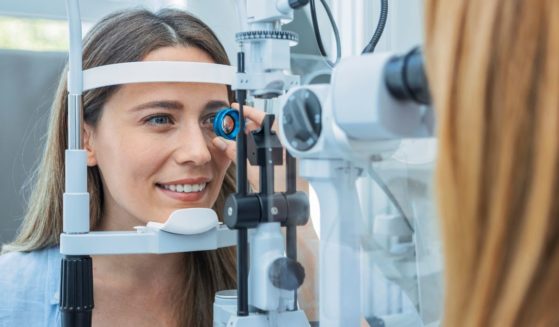 This stock photo shows a female patient receiving an eye exam from a doctor.