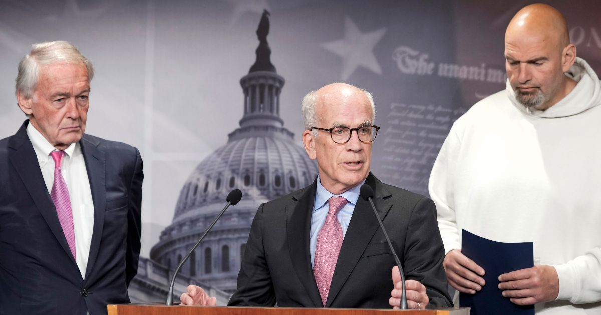Democrat Sens. John Fetterman of Pennsylvania, right, and Edward Markey o Massachusetts, left, listen as Peter Welch of Vermont speaks during a news conference Thursday on Capitol Hill in Washington.