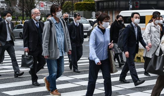 Commuters cross a street in central Tokyo in a file photo from March 13. As Japan's government eases its mask guidelines, seniors are enrolling in classes to help them re-learn how to smile.
