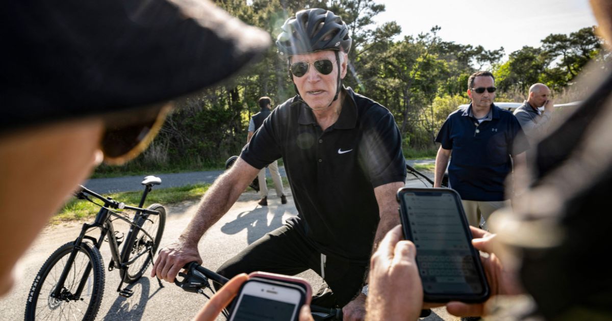 President Joe Biden stops to speak with the White House Press Corps while riding his bike in Cape Henlopen State Park in Rehoboth Beach, Delaware, on Sunday.