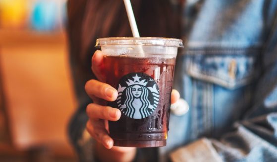 A woman holds an iced coffee from Starbucks in the above stock image.