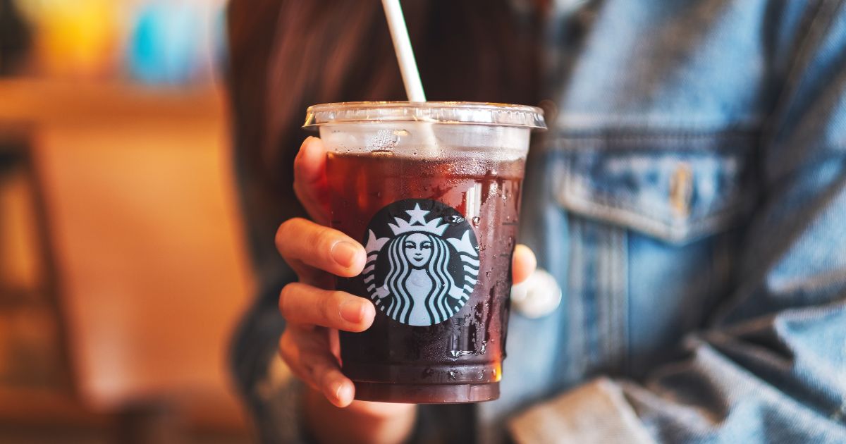 A woman holds an iced coffee from Starbucks in the above stock image.