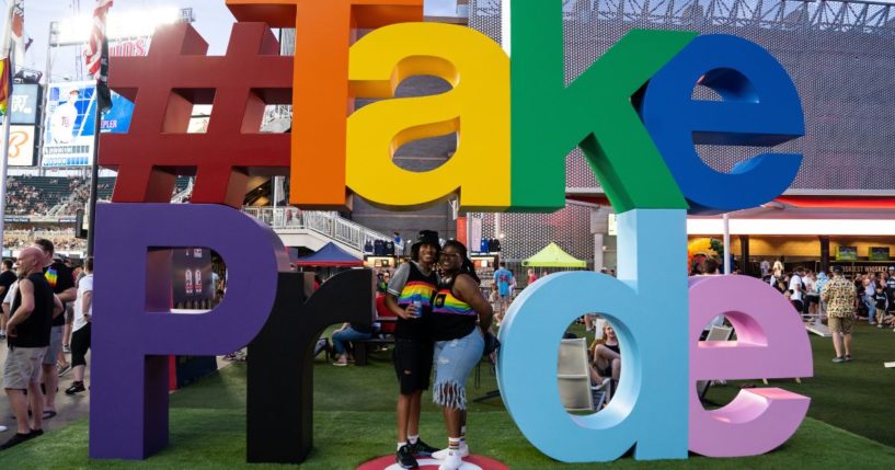 Fans pose for a photo in front of a Pride sign at Target Field in Minneapolis, Minnesota, on July 15, 2022.