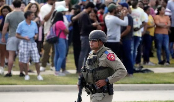 A law enforcement officer walks as people are evacuated from a shopping center in Allen, Texas, where a shooting occurred on Saturday.