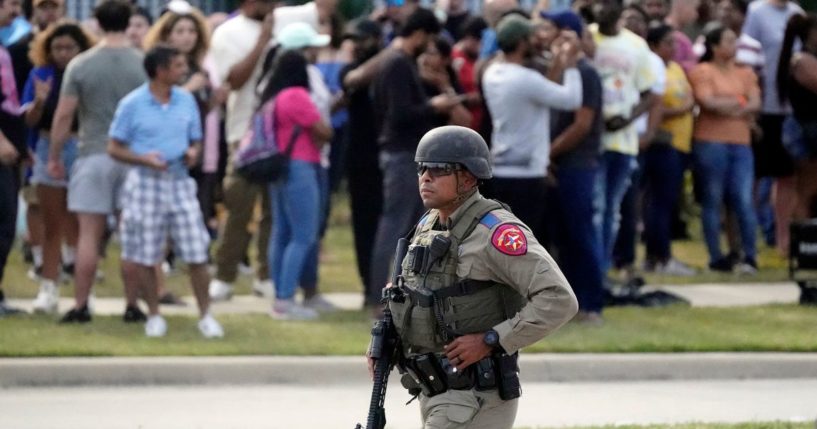 A law enforcement officer walks as people are evacuated from a shopping center in Allen, Texas, where a shooting occurred on Saturday.
