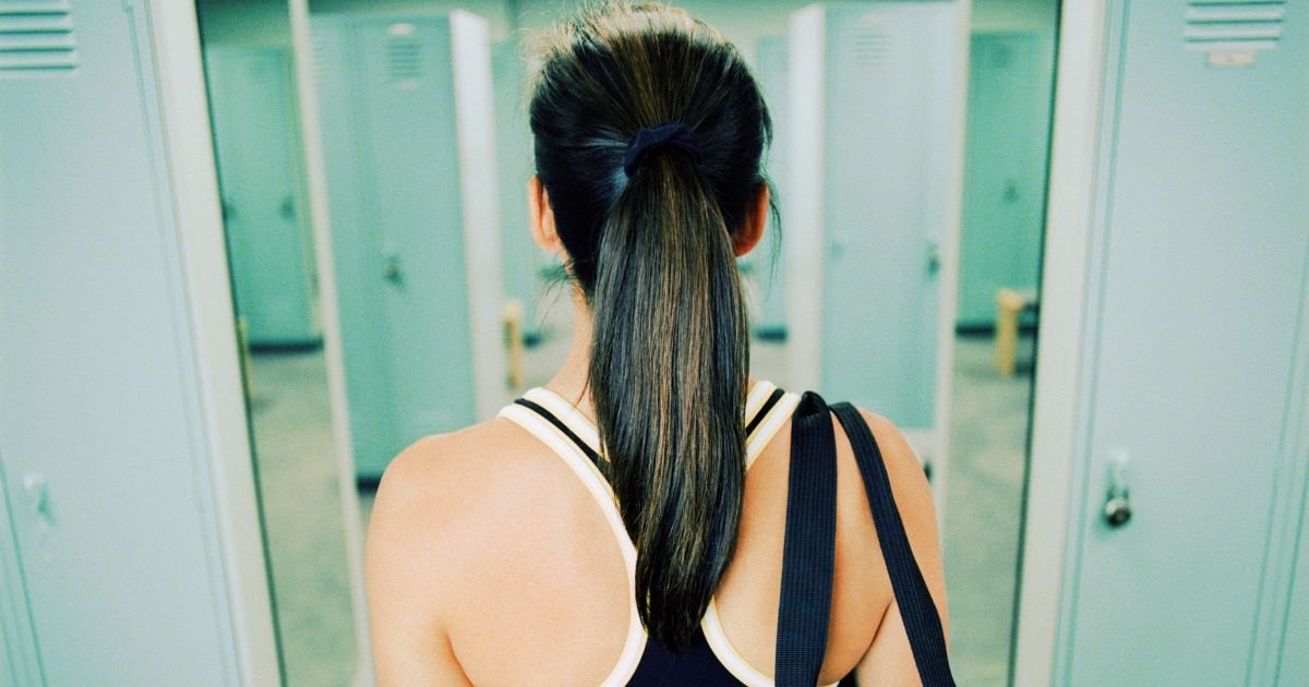 This stock image shows a woman entering a women's locker room at a gym.