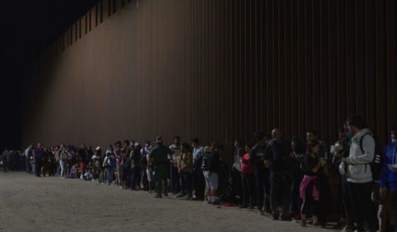 Migrants line up as they wait to be processed by US Border Patrol after illegally crossing the US-Mexico border in Yuma, Arizona, in the early morning of July 11, 2022.