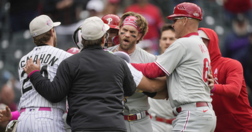 Bryce Harper being restrained by a player, and umpire and a coach