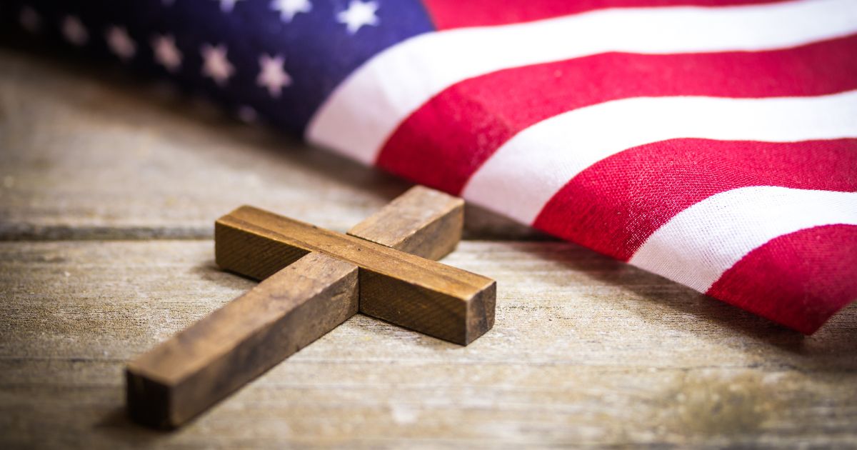 A wooden cross and American flag are seen in the above stock image.