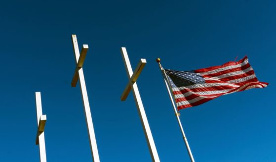 An American flag flies next to three crosses in this stock image.