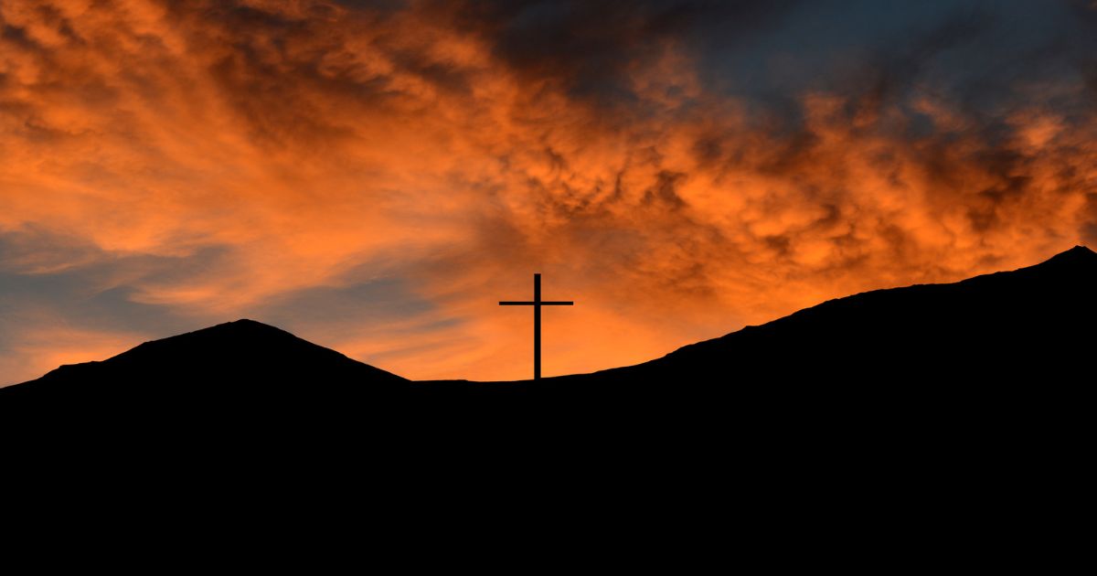 A mountaintop cross is silhouetted against the sunset on the U.S.-Mexican border.