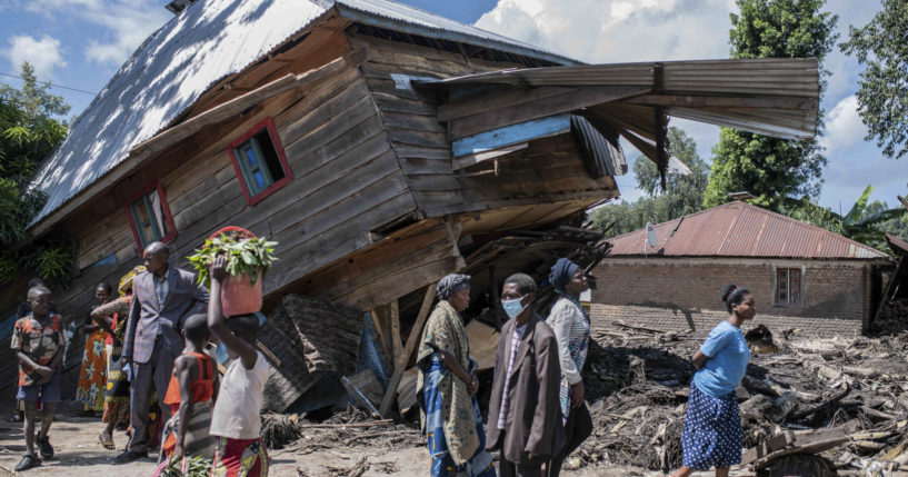 People walk next to a house destroyed by the floods in the village of Nyamukub, Congo, on Sunday.
