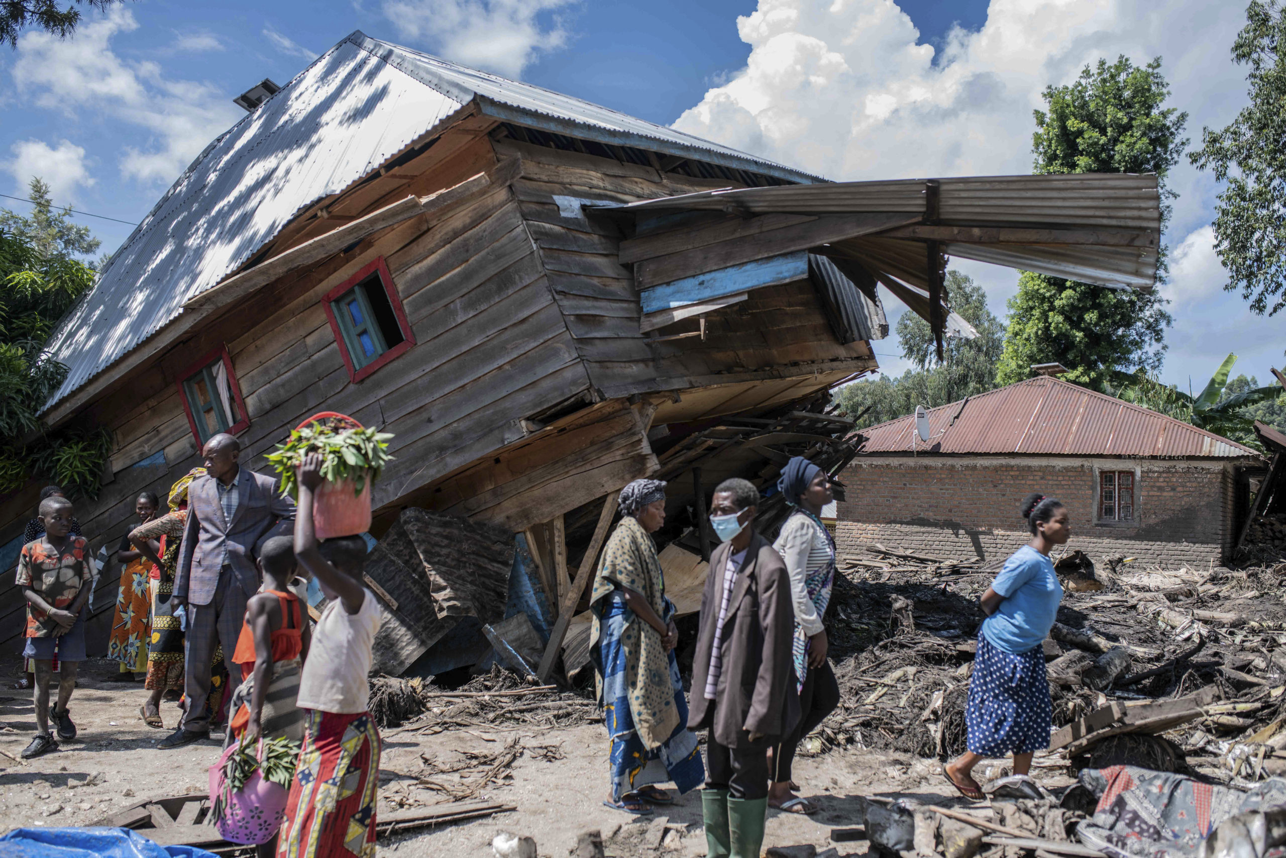People walk next to a house destroyed by the floods in the village of Nyamukub, Congo, on Sunday.