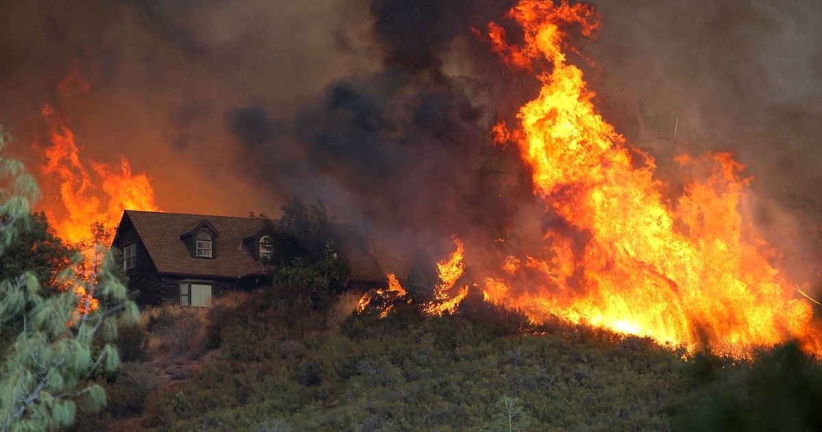 Flames from the Rocky Fire approach a house on July 31, 2015, in Lower Lake, California.