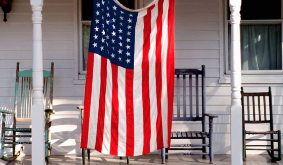 An American flag hangs from a porch in this stock image.