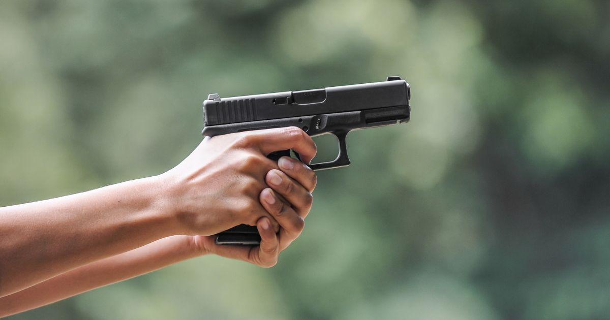 A man uses a handgun in this stock image.