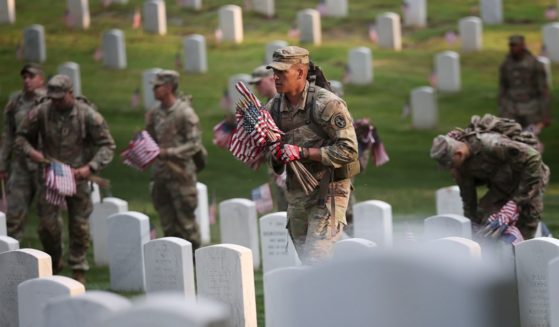 Members of the 3rd U.S. Infantry Regiment fan out Thursday to place flags at the headstones of U.S. military personnel buried at Arlington National Cemetery, in preparation for Memorial Day.