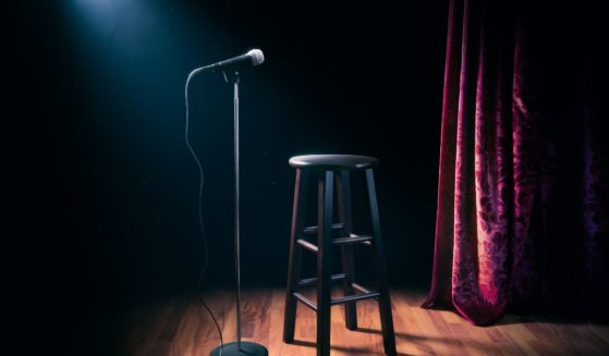 A microphone and stool stand on an empty stage in this stock image.