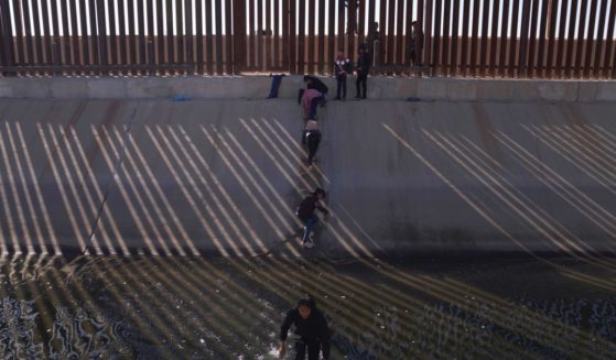 Migrants illegally cross into the United States from Mexico via a hole cut in the border fence in El Paso, Texas, on December 21.
