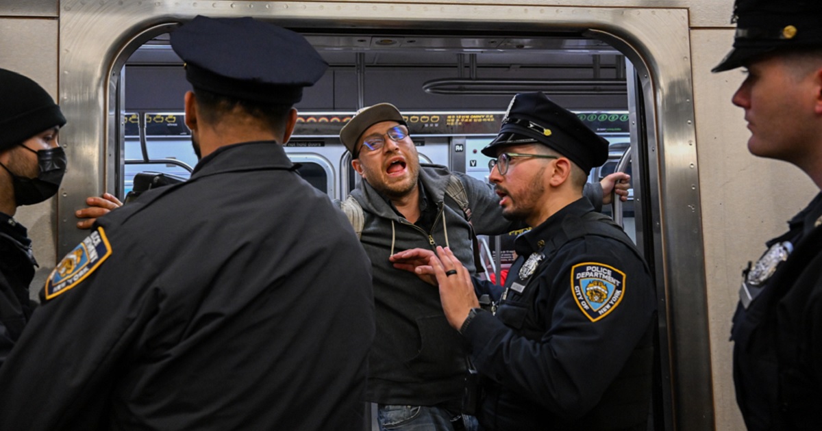 A protester holds a subway door open Saturday as police try to maintain order in New York City amid demonstrations over the death of a man in a confrontation on Monday.