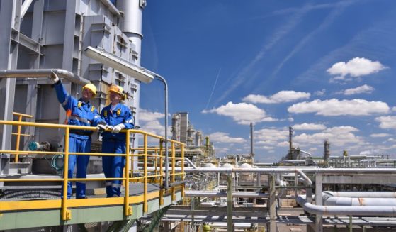 Men work at an oil refinery in this stock image.