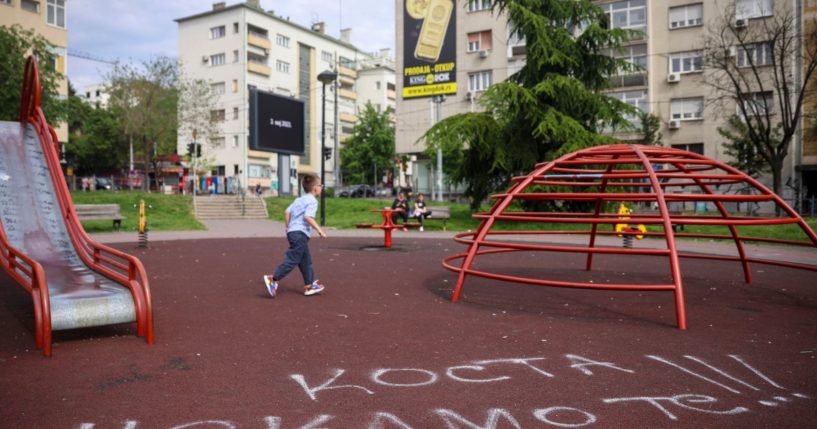 A boy walks past graffiti on a playground that reads: "Kosta we are waiting for you" in Belgrade, Serbia, on Saturday.