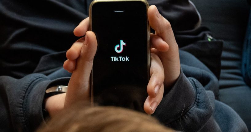 In this photo illustration, a boy looks at the TikTok app on a smartphone screen.