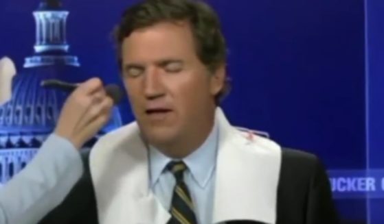 Tucker Carlson speaks with his makeup artist while getting reading for a show.