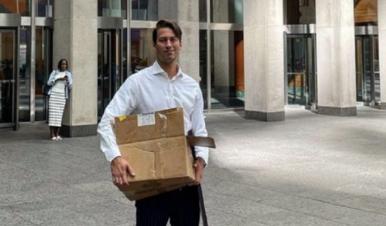 Former Fox News producer Alexander McCaskill carries a box with his personal belongings after his departure from the network.