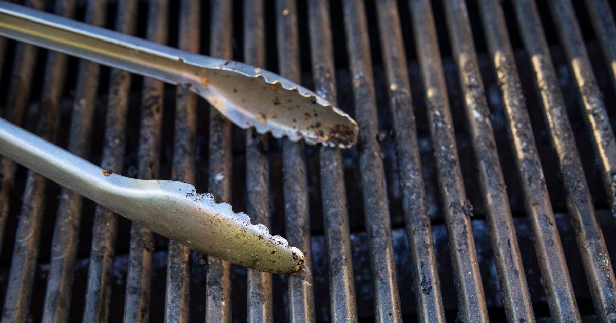 A stock photo shows barbecue tongs on a grill.