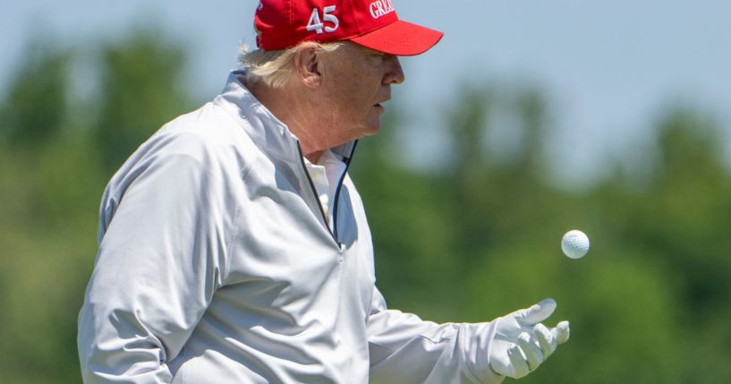 Former President Donald Trump tosses his ball as he plays golf at Trump National Golf Club on Thursday in Sterling, Virginia.