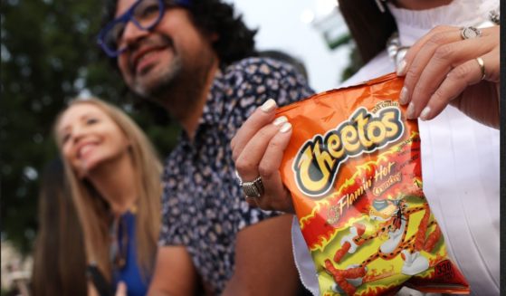 A woman holds bag of Flamin' Hot Cheetos during a screening of the film “Flamin’ Hot,” hosted by President Joe Biden and first lady Jill Biden on the South Lawn of the White House on Thursday. The movie purports to tell the "true story" of Richard Montanez, a janitor at Frito-Lay who claimed to have created the recipe for Flamin’ Hot Cheetos, which turned the snack into a global phenomenon. But a Los Angeles Times report indicates Montanez had nothing to do with the development of the product.