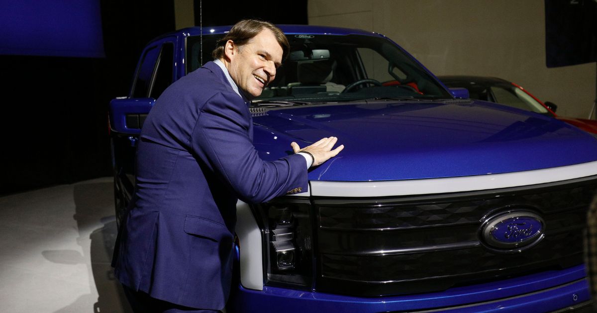 Ford CEO Jim Farley pats a Ford F-150 Lightning electric pickup truck in a file photo from on February.