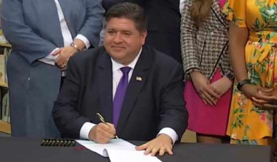 In this screenshot from a livestream broadcast by the State of Illinois, Gov. J.B. Pritzker signs a bill requiring the state's libraries to uphold a pledge not to ban material because of partisan disapproval, starting on Jan. 1, 2024. If they refuse, they will not receive state funding.