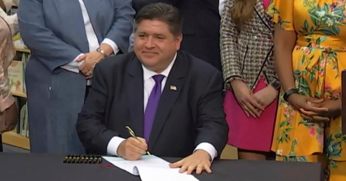 In this screenshot from a livestream broadcast by the State of Illinois, Gov. J.B. Pritzker signs a bill requiring the state's libraries to uphold a pledge not to ban material because of partisan disapproval, starting on Jan. 1, 2024. If they refuse, they will not receive state funding.