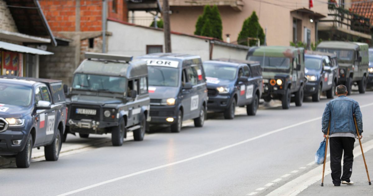 A man walks past a convoy of NATO-led peacekeeping force KFOR vehicles parked on a street in the town of Zvecan, northern Kosovo, Thursday.