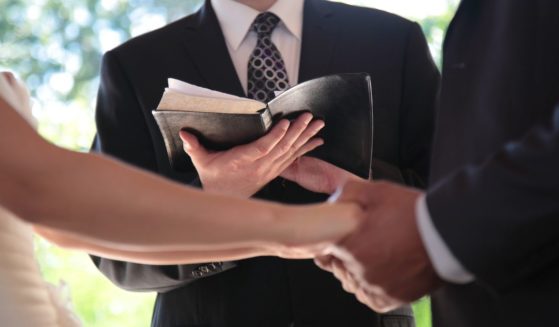 An undated stock photo shows a bride and groom holding hands in front of a pastor with a Bible during a wedding ceremony in Vancouver, British Columbia.