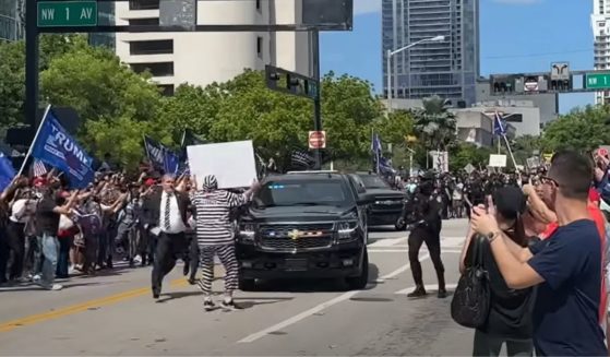 Anti-Trump demonstrator Dominic Santana walks in front of Trump's motorcade in Miami, Florida, on Tuesday.