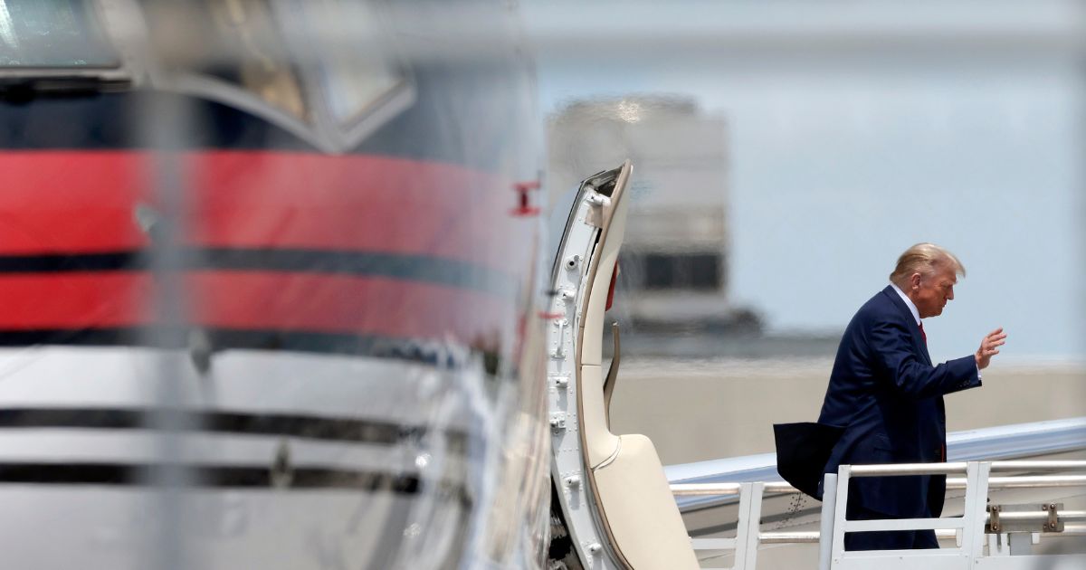 Former President Donald Trump waves as he arrives at the Miami International Airport on Monday.