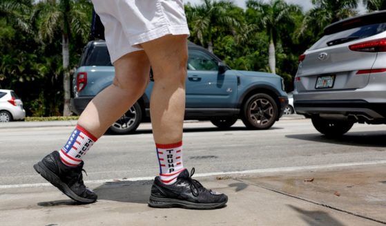 A supporter of former U.S. President Donald Trump wears socks with Trump on them as they walk past the Trump National Doral resort and await his arrival in Doral, Florida, on Monday.