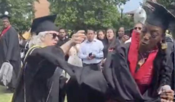 A recent college graduate rips the microphone away from a faculty member. (@rahsh33m / Twitter)