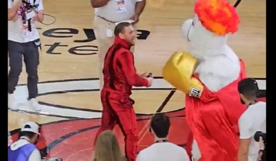 Mixed martial arts fighter Conor McGregor sizes up Burning, the Miami Heat mascot, before throwing a punch during a mid-game skit June 9 in Miami.